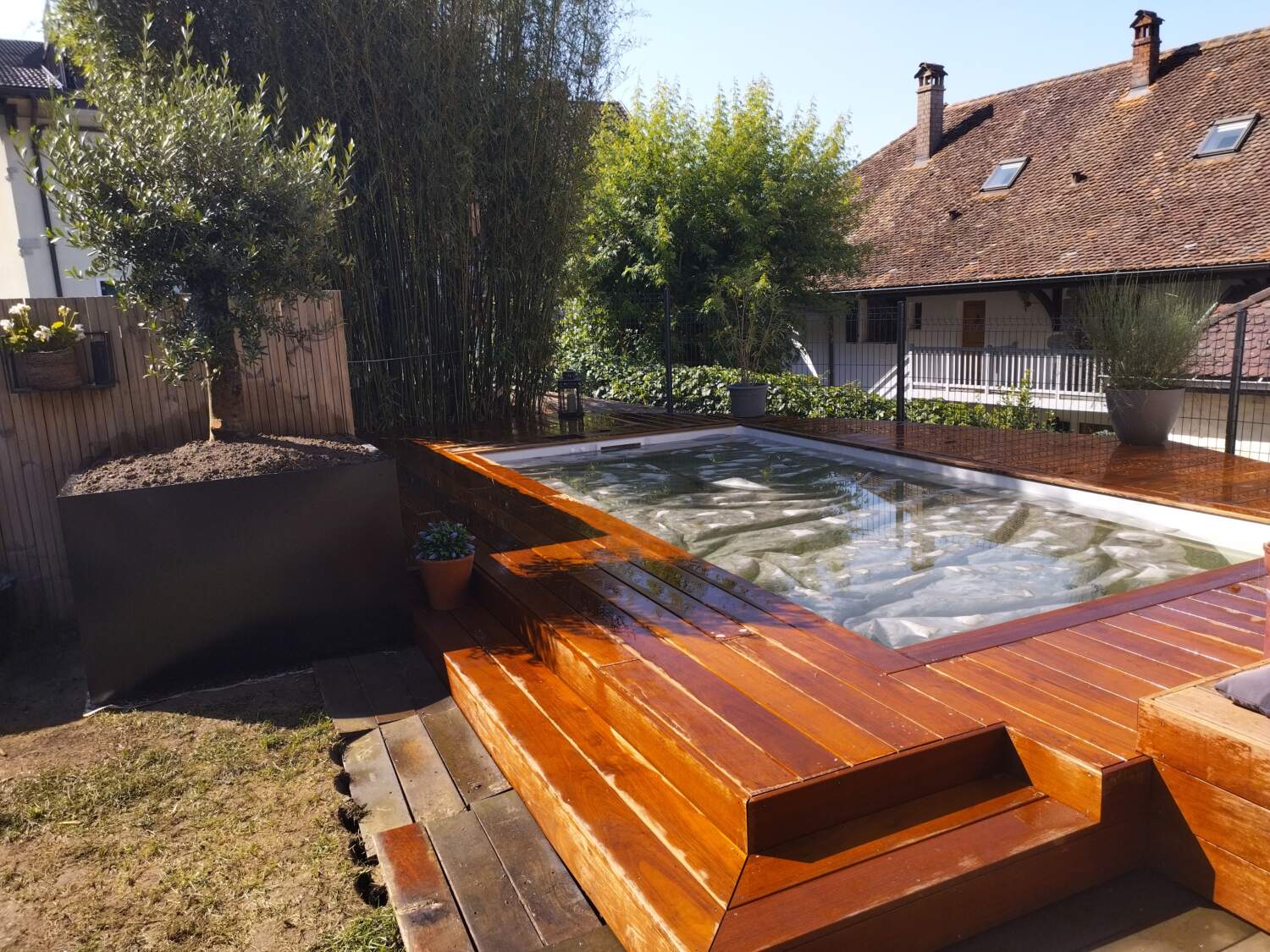 Piscine extérieure avec terrasse bois et jardinière maçonnée